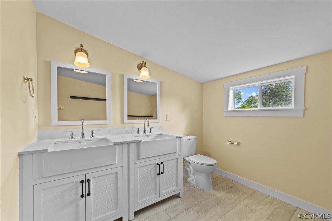 Bathroom with hardwood / wood-style floors, oversized vanity, toilet, and dual sinks