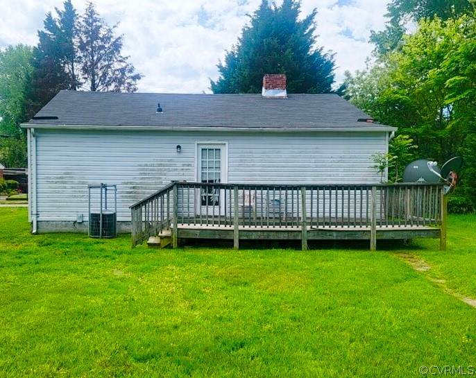 Back of house with a deck and a lawn