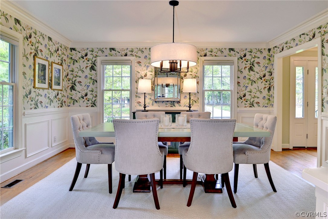Dining area featuring plenty of natural light, a notable chandelier, crown molding, and light wood-type flooring