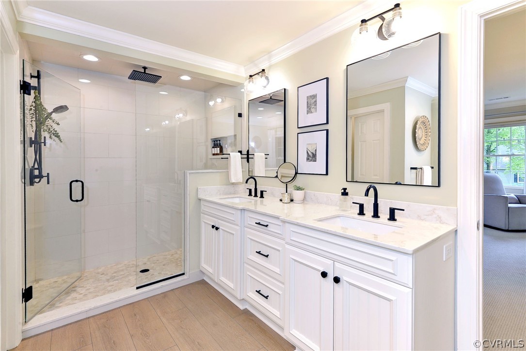 Bathroom featuring a shower with door, hardwood / wood-style floors, crown molding, and dual vanity