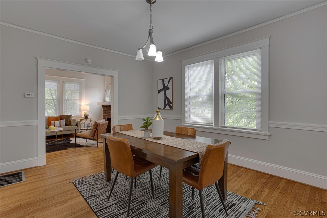 Dining space with a wealth of natural light, crown molding, and light hardwood / wood-style flooring