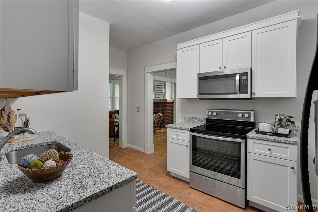 Kitchen with white cabinets, light tile floors, and stainless steel appliances