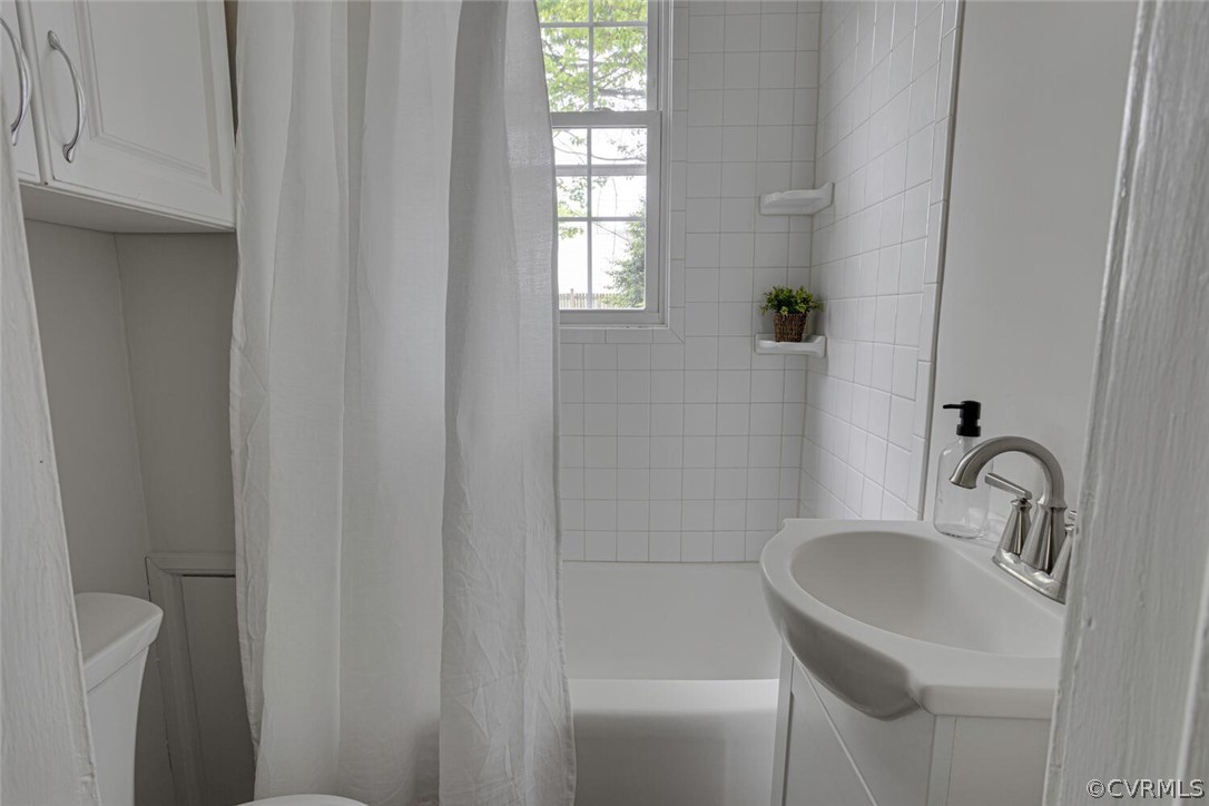 Full bathroom featuring vanity, a wealth of natural light, shower / bath combination with curtain, and toilet