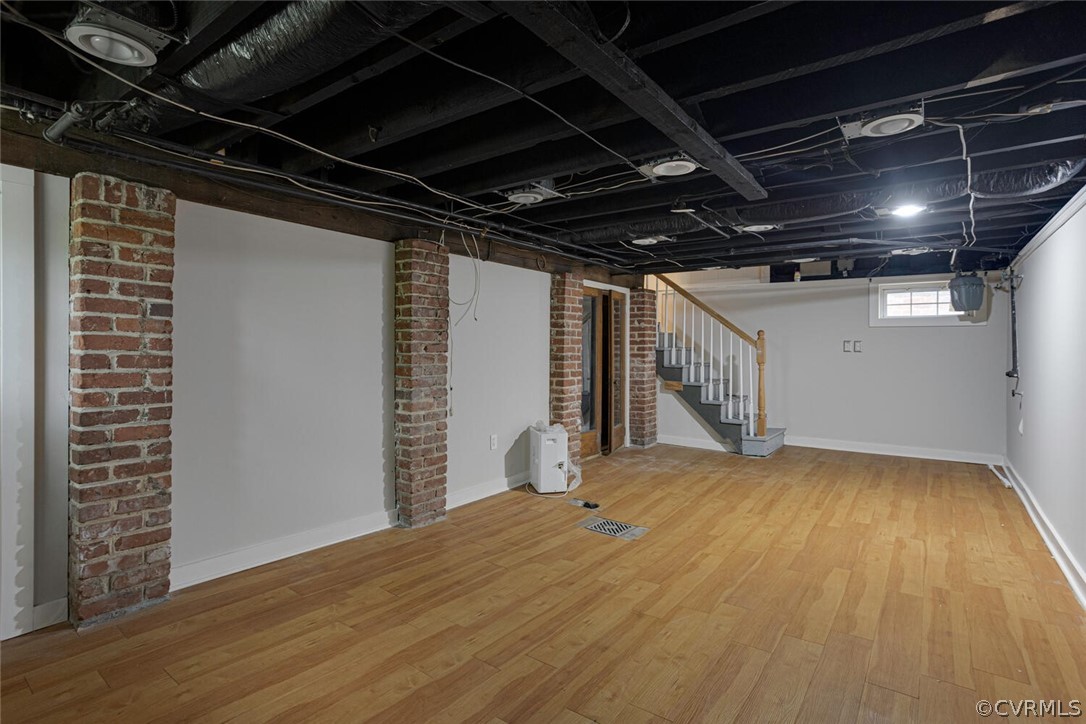 Basement featuring light hardwood / wood-style floors and brick wall