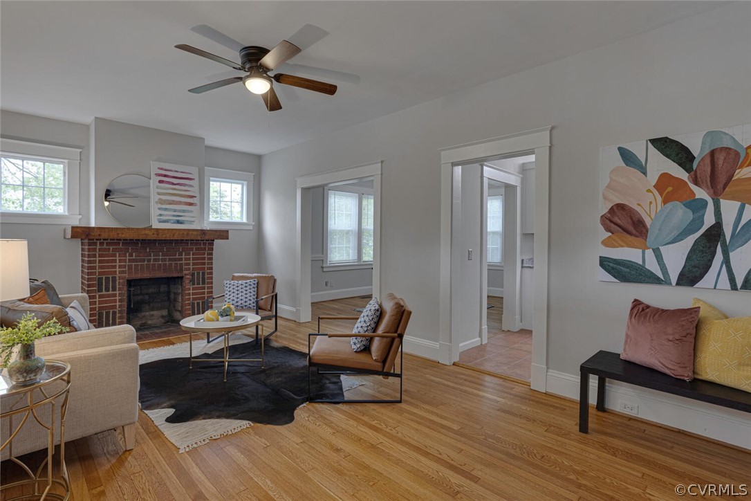 Living room featuring light hardwood / wood-style flooring, ceiling fan, and a brick fireplace