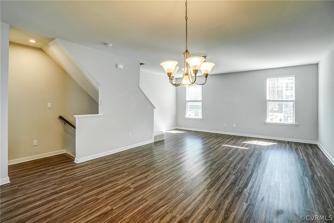 Unfurnished room with a healthy amount of sunlight, a chandelier, and dark hardwood / wood-style floors