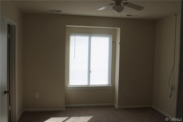 Unfurnished room with ceiling fan, carpet, and a wealth of natural light