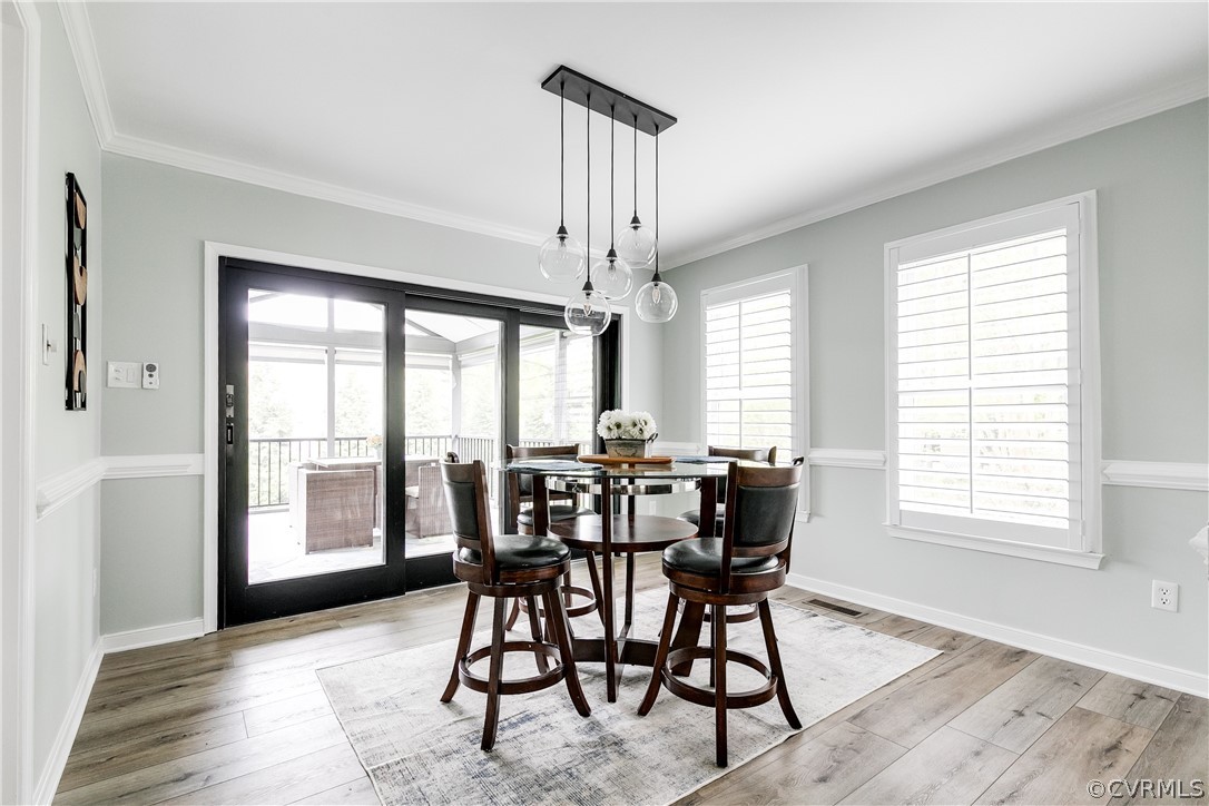 Dining space featuring a healthy amount of sunlight, light hardwood / wood-style flooring, and crown molding