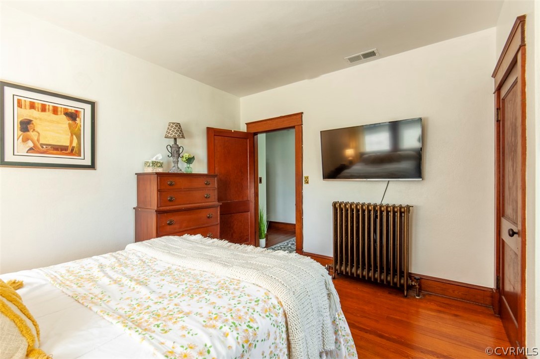 Bedroom featuring vaulted ceiling, dark hardwood / wood-style flooring, and radiator