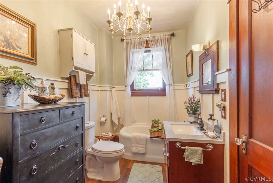 Full bathroom featuring vanity, hardwood / wood-style floors, an inviting chandelier, bathtub / shower combination, and toilet