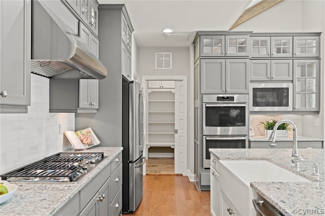 Cabinetry extends to ceiling and features beautiful crown. The pocket door leads to 1st floor laundry room with custom drop zone with shelving, and cabinetry storage over washer & dryer. Walk in pantry right beside fridge.
