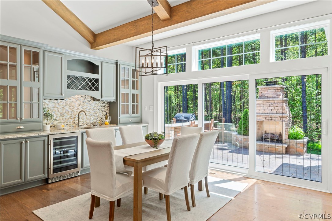 Beautiful eating area with additional cabinetry with wet bar, wine cooler, and tons of natural light from a wall that is practically all glass. The only view out of these windows and doors is natural green space.