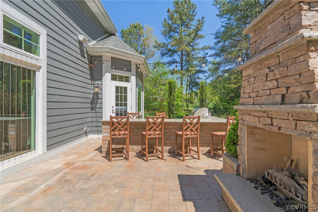 Paver patio with stacked stone gas fireplace. Sliding doors to left lead to dining area inside, and primary patio access door can be seen straight ahead.