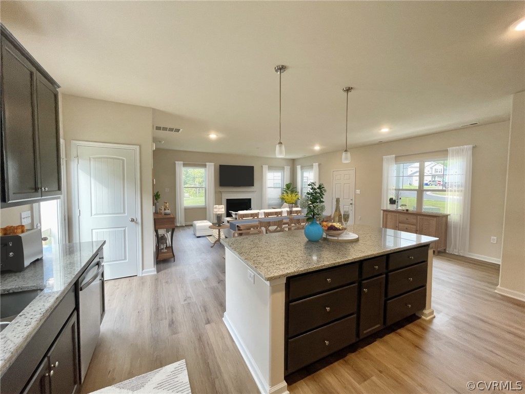 Kitchen featuring a kitchen island, light hardwood / wood-style flooring, light stone countertops, and stainless steel dishwasher