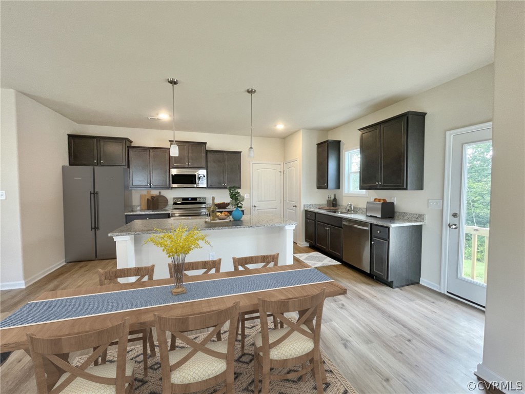Kitchen featuring a kitchen island, a healthy amount of sunlight, appliances with stainless steel finishes, and light hardwood / wood-style floors