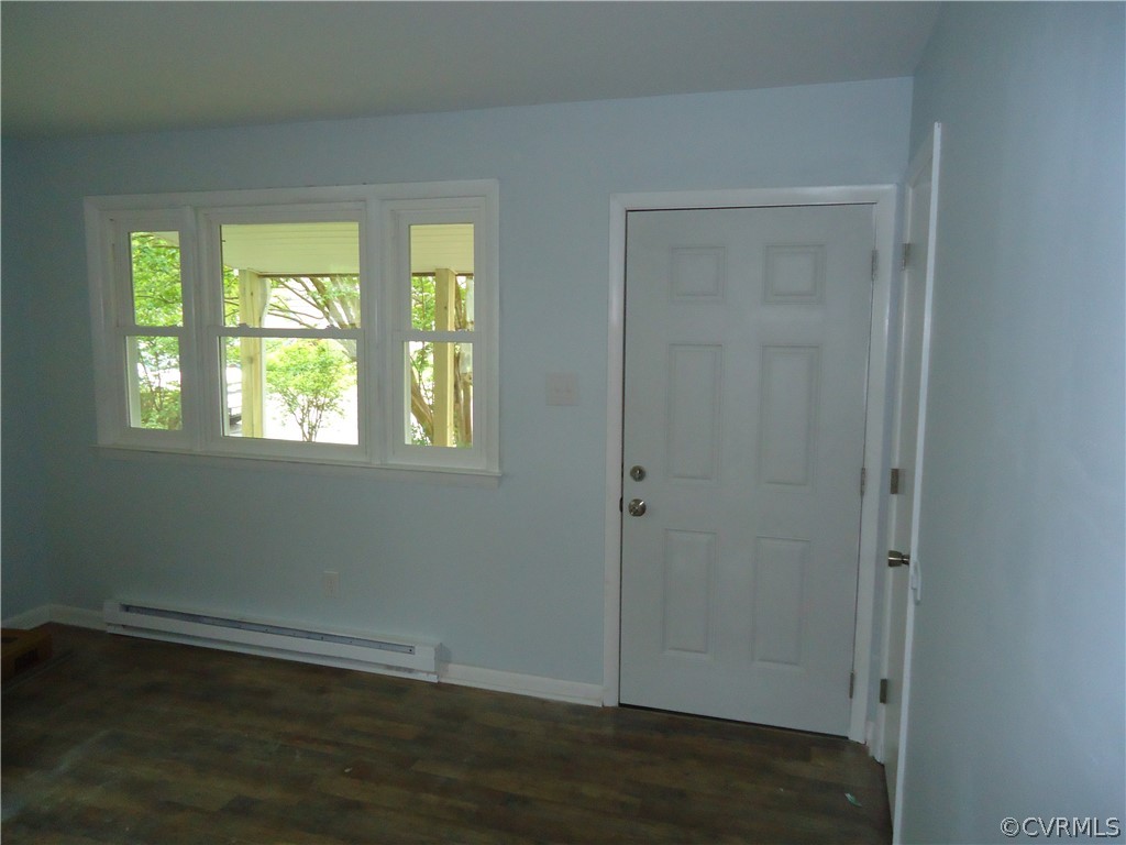 Foyer entrance with dark hardwood / wood-style floors and a baseboard heating unit