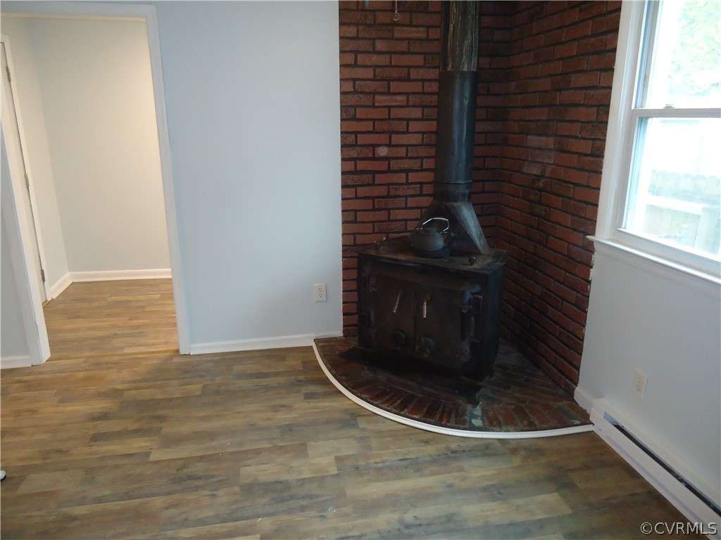 Interior details featuring a wood stove, dark hardwood / wood-style flooring, and a baseboard radiator