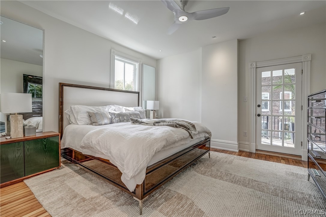 Bedroom featuring ceiling fan, hardwood / wood-style flooring, access to exterior, and multiple windows