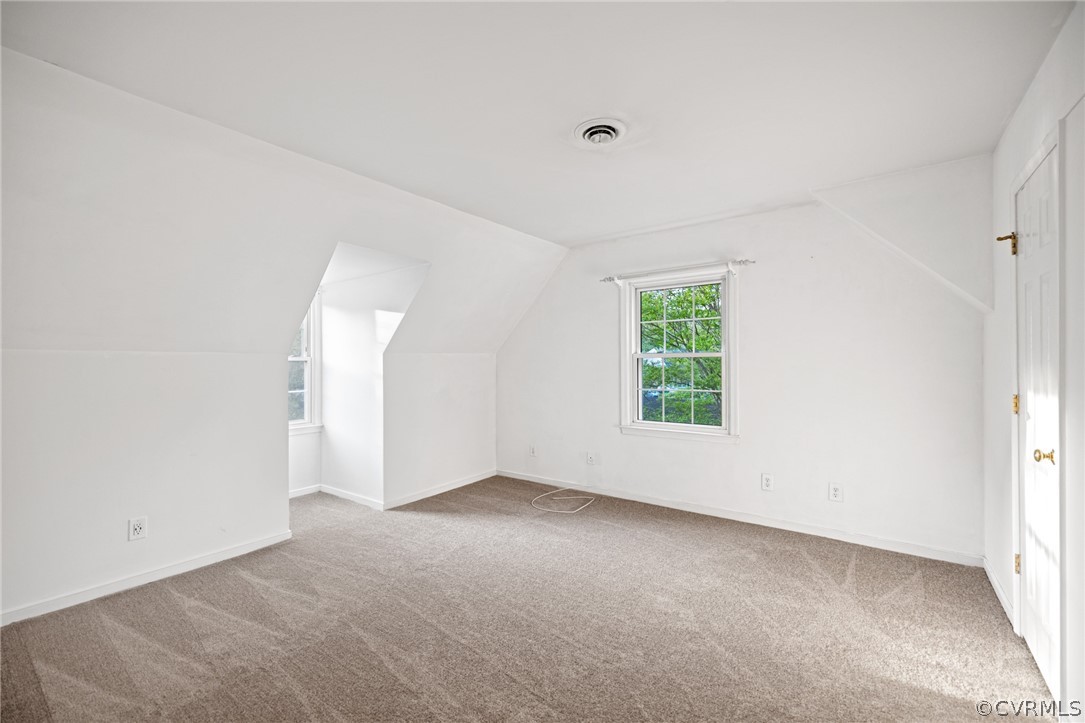 Additional living space with lofted ceiling and carpet flooring