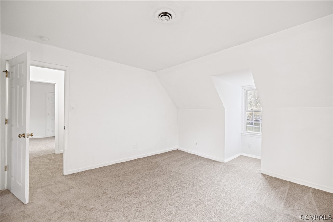 Bonus room with vaulted ceiling and light carpet
