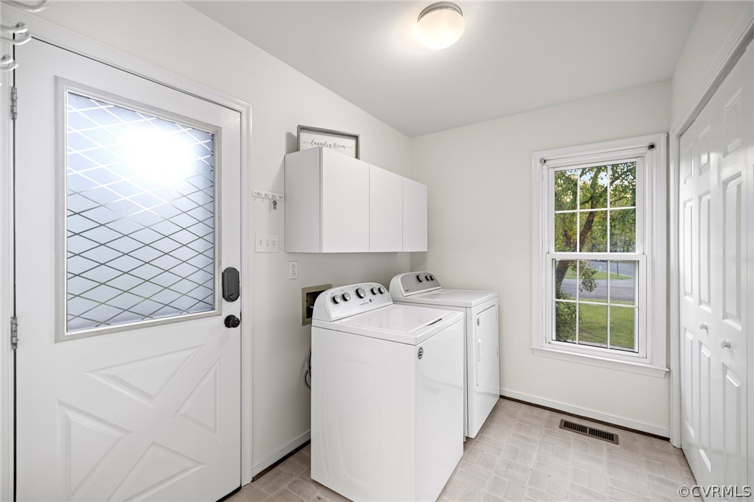 Washroom with a wealth of natural light, washer and clothes dryer, and light tile flooring
