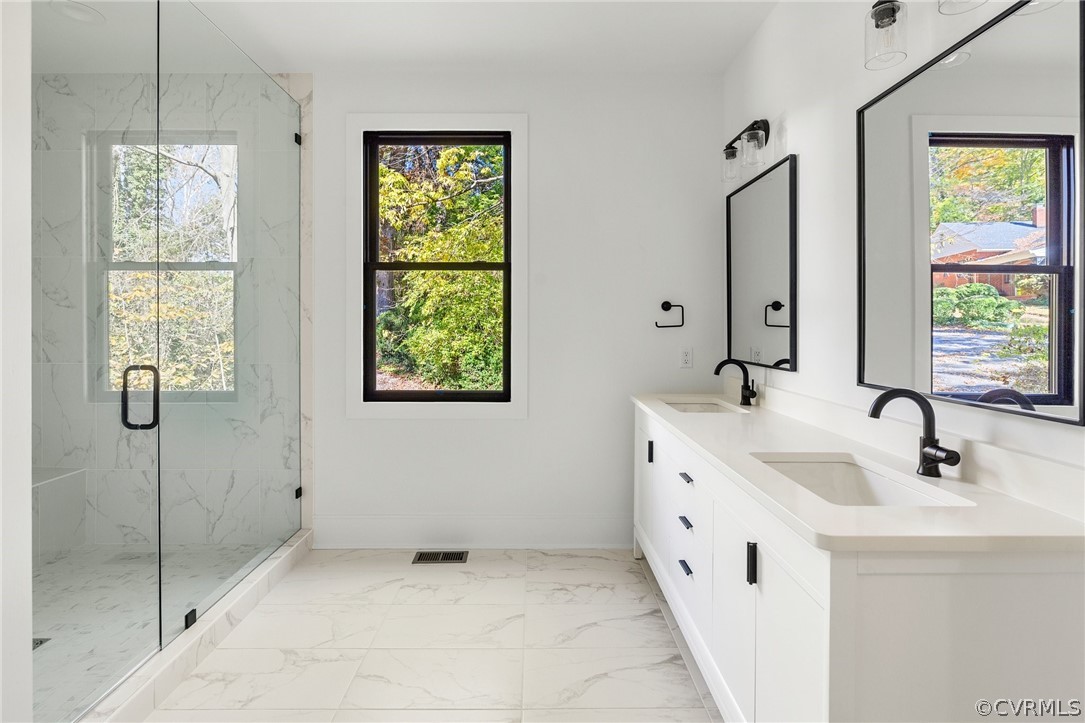 Primary bathroom with tile floors, natural light, double vanity, and a glass shower 
*All photos represent a similar home by the same builder, Center Creek Homes*