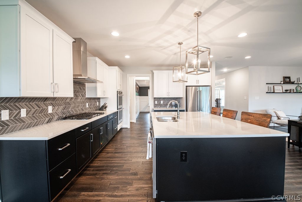 Kitchen featuring backsplash, stainless steel appliances, wall chimney exhaust hood, sink, and dark hardwood / wood-style flooring