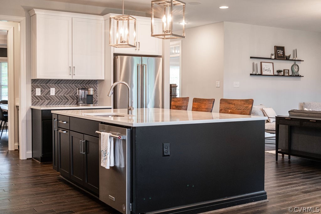Kitchen featuring appliances with stainless steel finishes, dark hardwood / wood-style floors, tasteful backsplash, sink, and pendant lighting