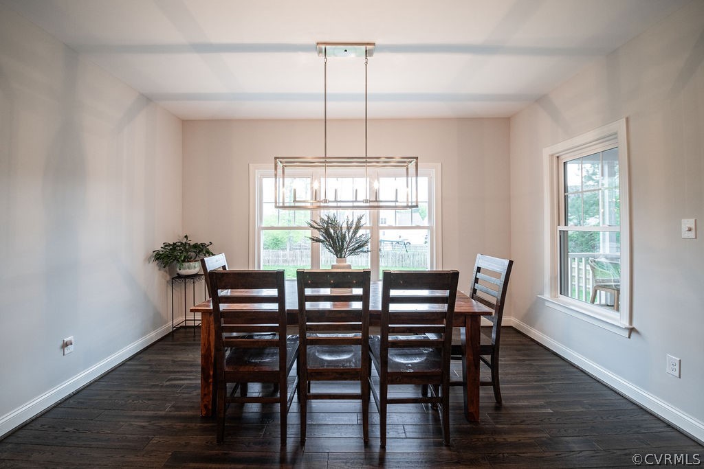 Dining room featuring a healthy amount of sunlight, dark hardwood  flooring, and an inviting chandelier