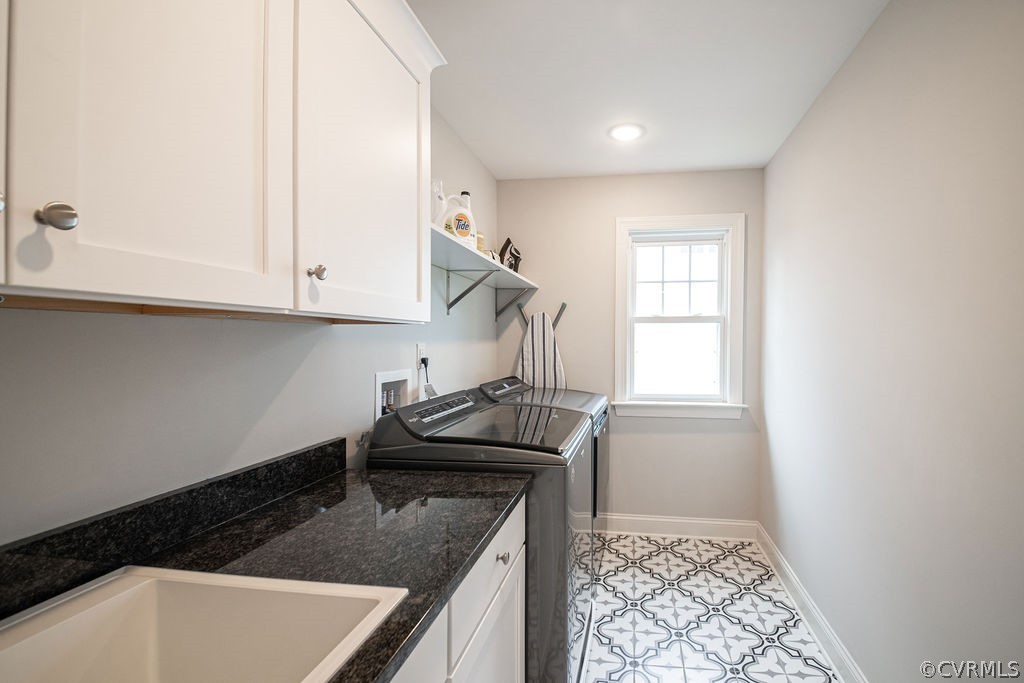 Large laundry room featuring cabinets, washer and clothes dryer, sink, and light tile floors