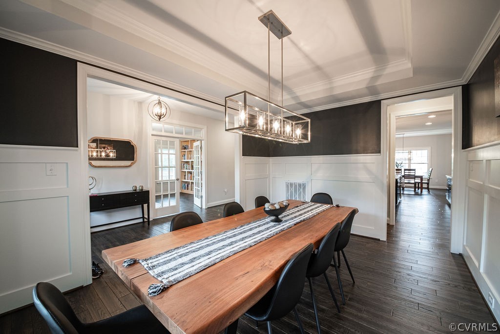 Dining room with dark hardwood / wood-style floors, french doors, a tray ceiling, and crown molding