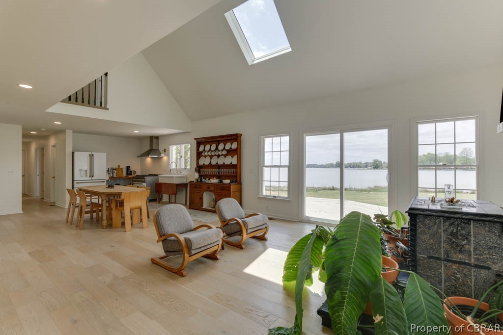 Living room with a skylight, a water view, and high vaulted ceiling