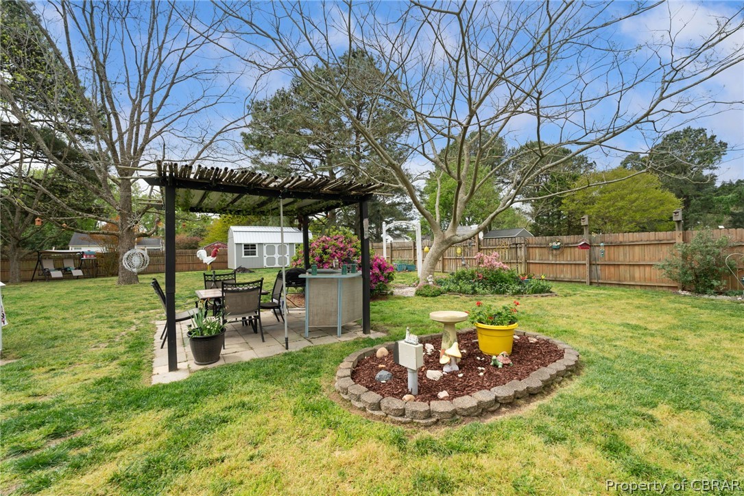 View of yard with a patio area, an outdoor structure, and a pergola