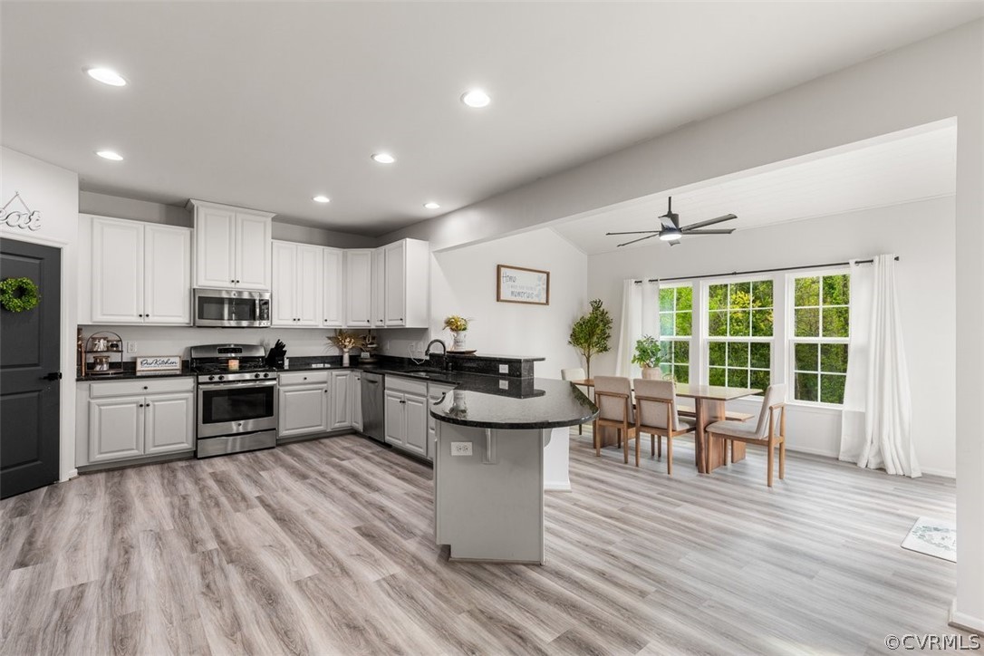 Kitchen with appliances with stainless steel finishes, kitchen peninsula, and light wood-type flooring