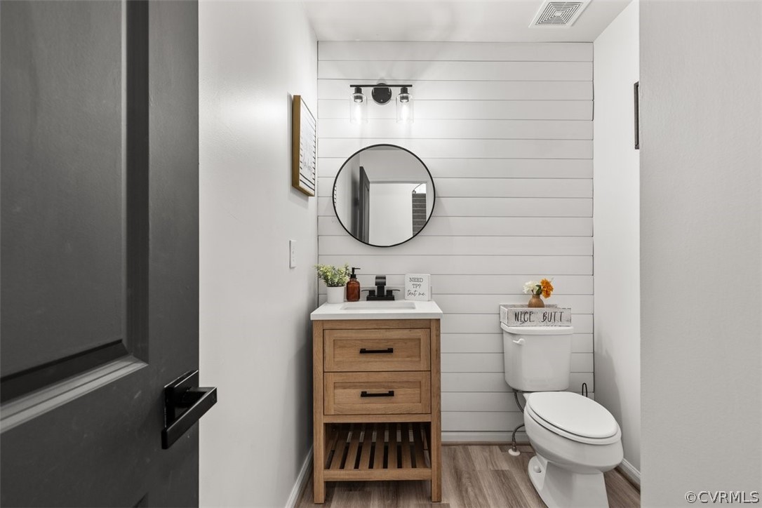 Bathroom with hardwood / wood-style flooring, toilet, and vanity