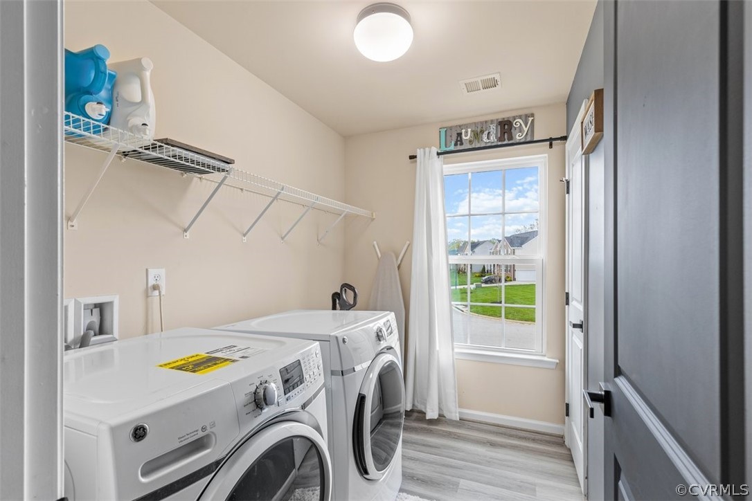 Washroom with light hardwood / wood-style floors, washing machine and dryer, and hookup for a washing machine