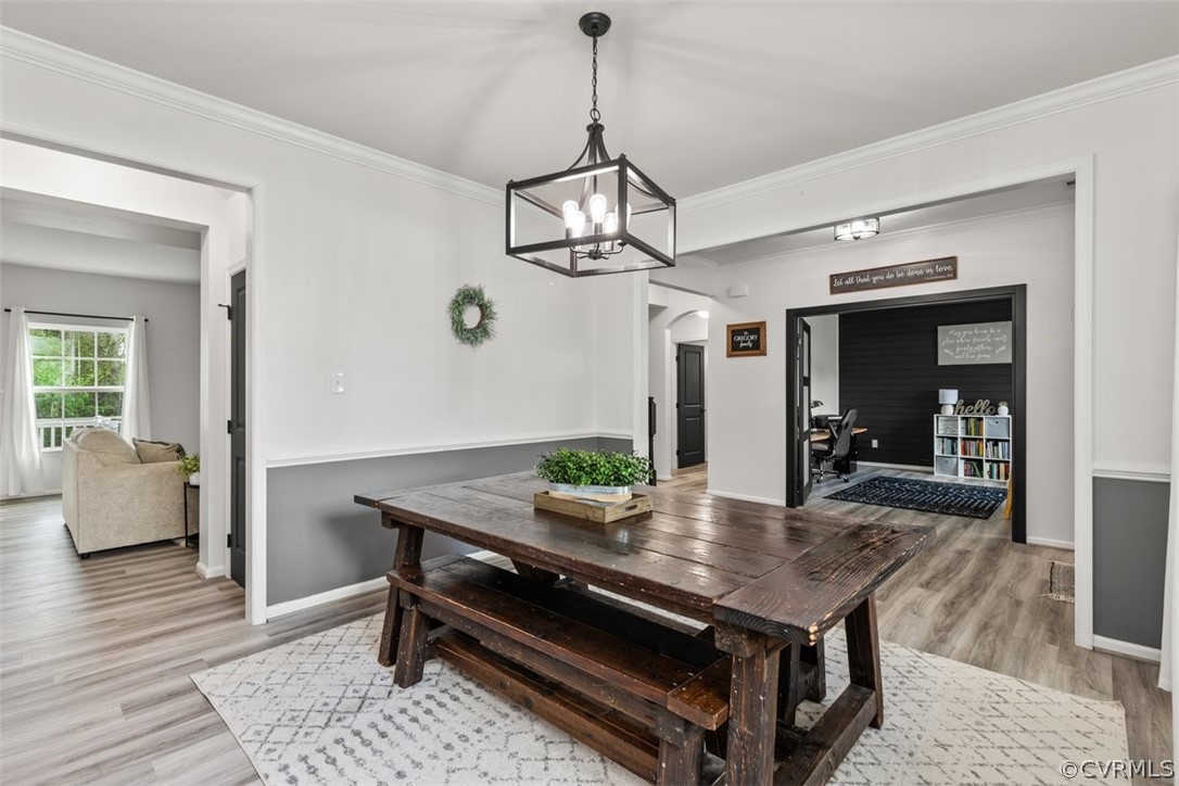 Dining area featuring ornamental molding, a chandelier, and light wood-type flooring