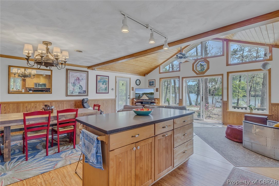 Kitchen featuring a kitchen island, light hardwood / wood-style flooring, vaulted ceiling with beams, ceiling fan with notable chandelier, and rail lighting