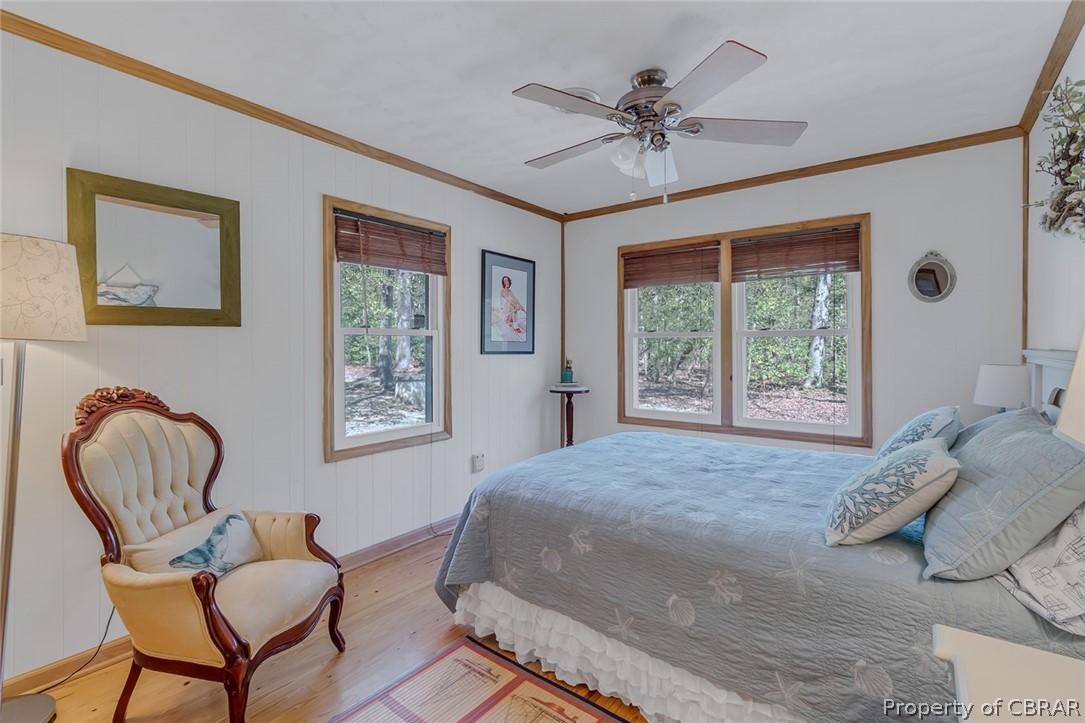 Bedroom with ceiling fan, crown molding, hardwood / wood-style flooring, and multiple windows
