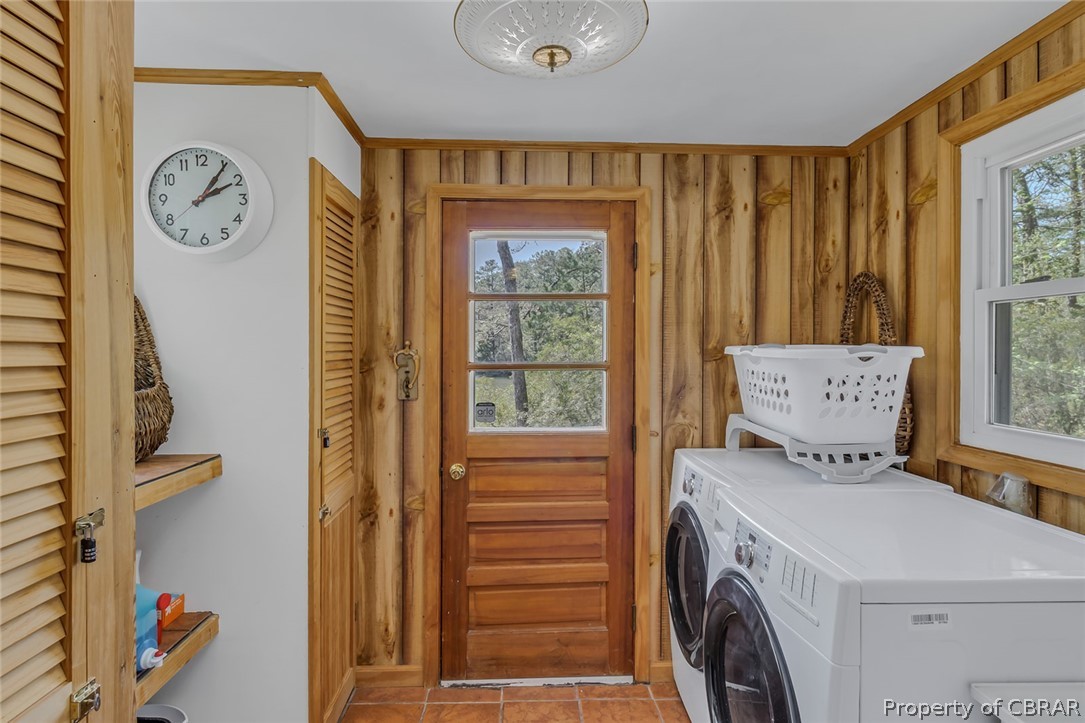Laundry area with washer and dryer, wooden walls, and light tile floors