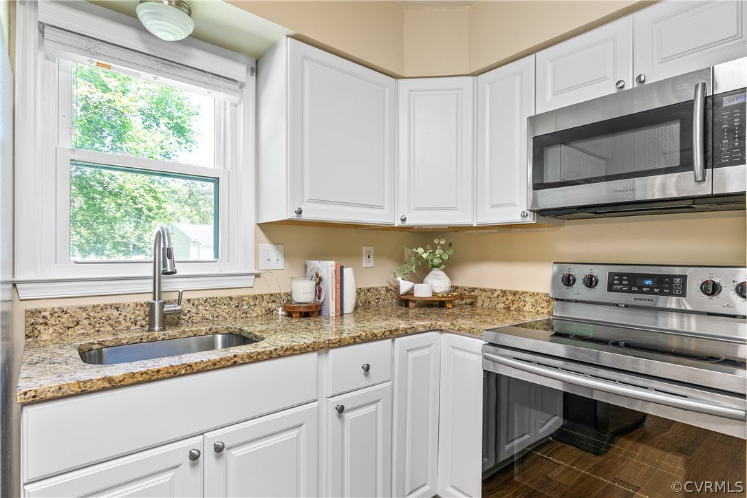 Kitchen with sink, white cabinetry, stainless steel appliances, and light stone counters