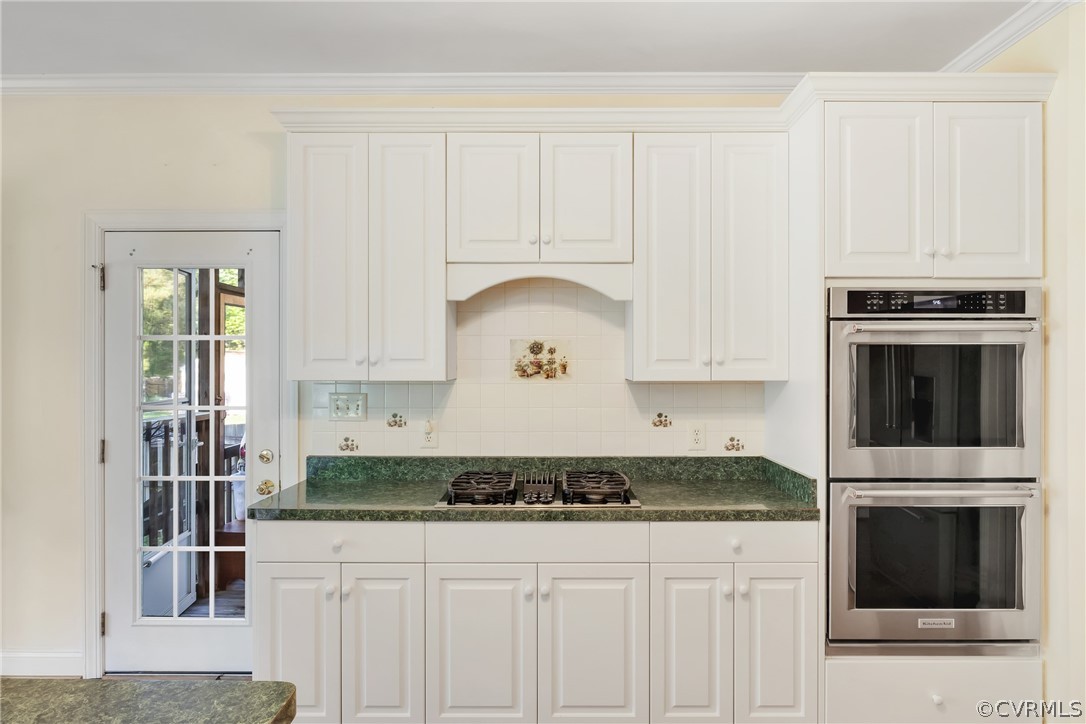 Kitchen featuring ornamental molding, tasteful backsplash, appliances with stainless steel finishes, and white cabinets