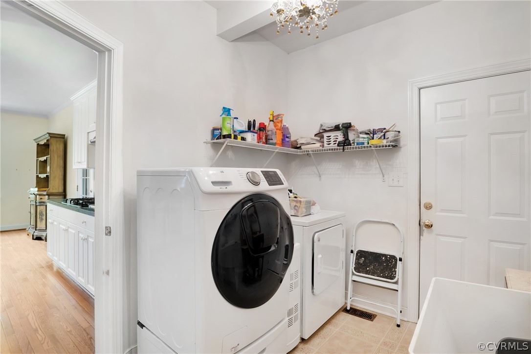 Laundry room with washer and dryer, a notable chandelier, and light tile floors