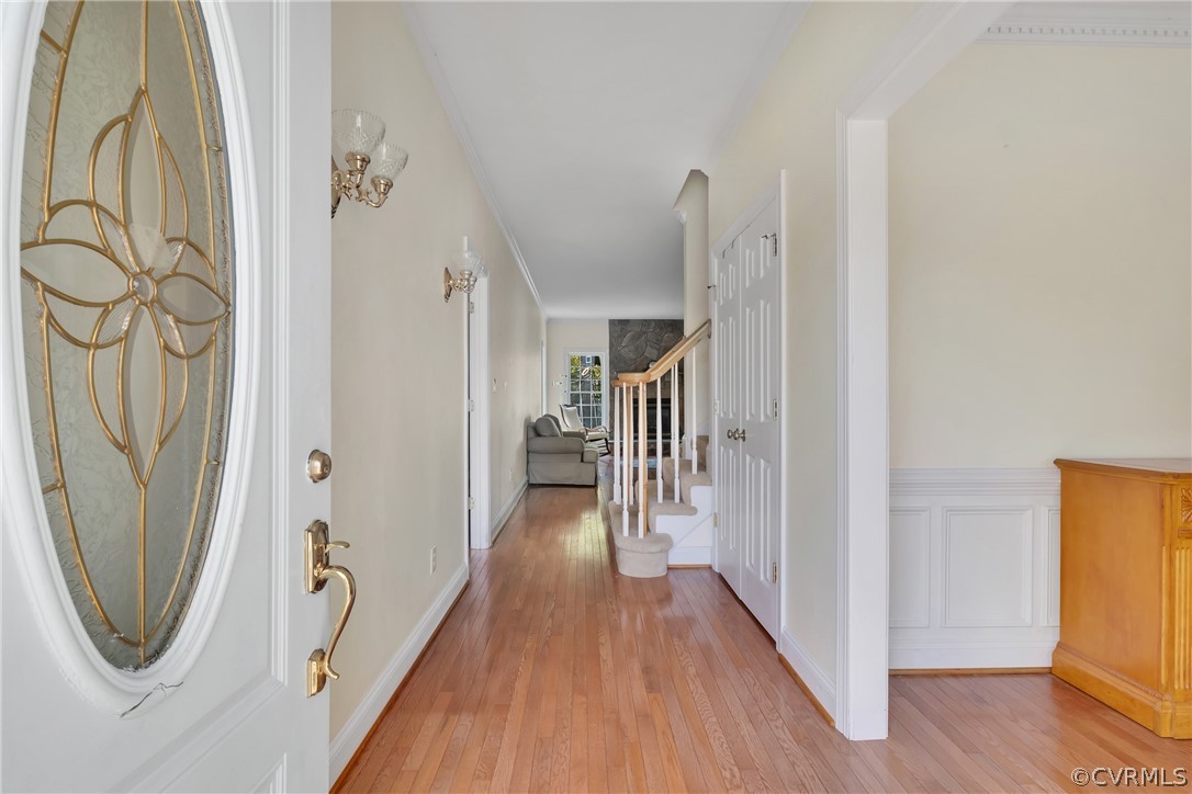 Foyer with light hardwood / wood-style floors and crown molding