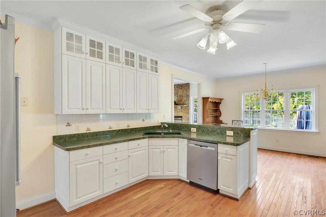 Kitchen featuring tasteful backsplash, white cabinetry, light wood-type flooring, and stainless steel dishwasher