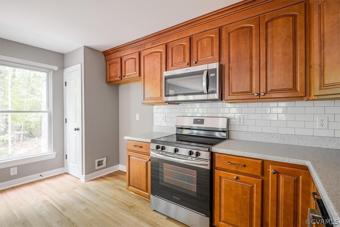 Kitchen with backsplash, stainless steel appliances, and light wood-type flooring