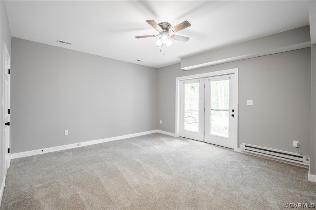Carpeted spare room with french doors, a baseboard heating unit, and ceiling fan
