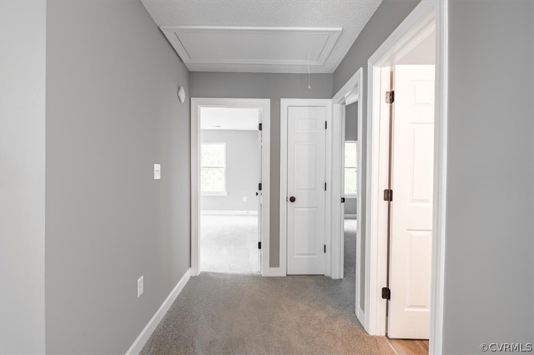 Corridor with light colored carpet and a textured ceiling
