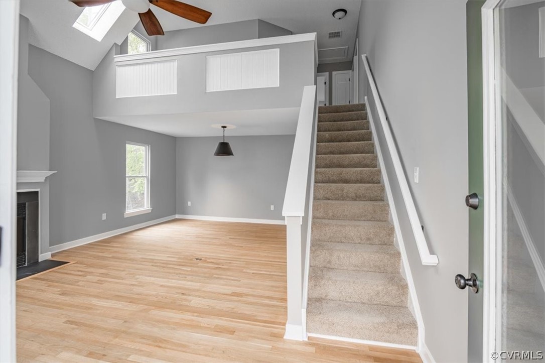 Staircase featuring a skylight, ceiling fan, and light wood-type flooring