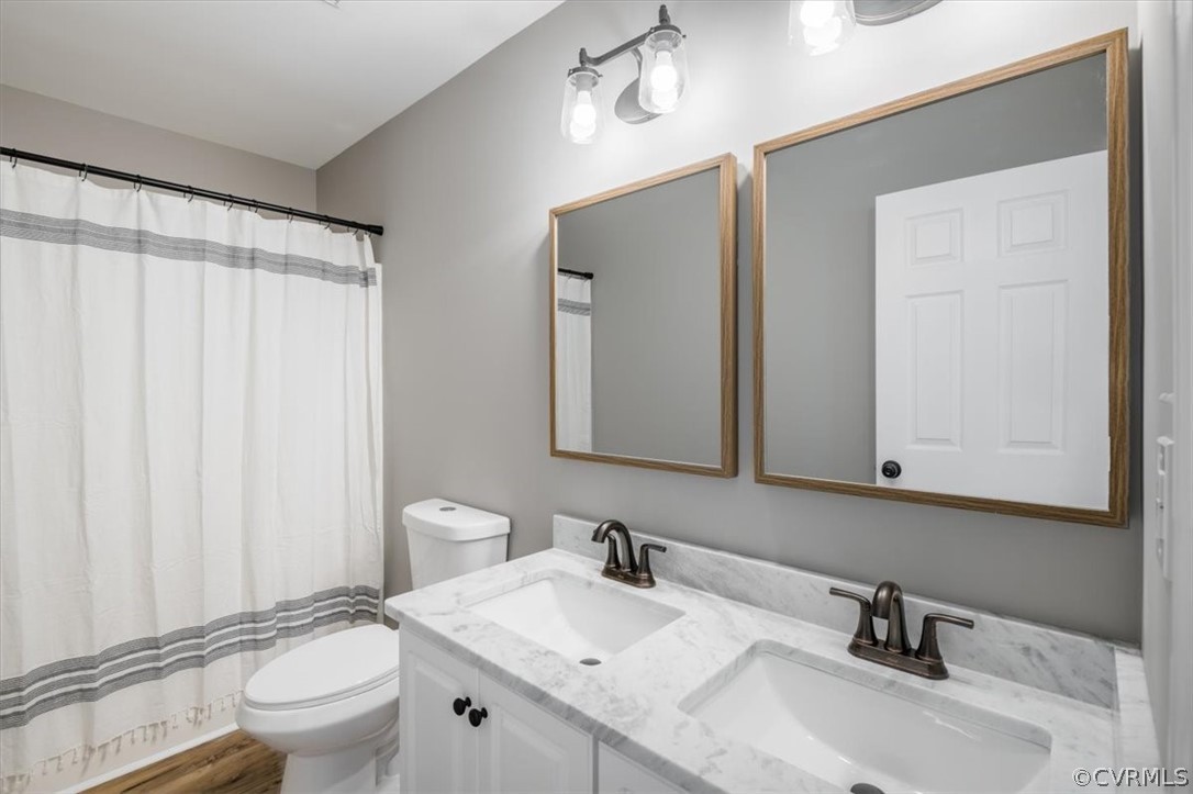 Bathroom with hardwood / wood-style floors, double vanity, and toilet